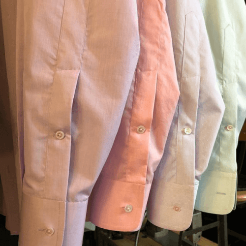 The cuffs of four dress shirts hanging in a line